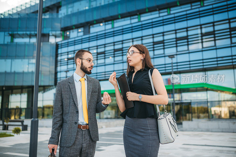 Business couple in front of the office building communicating